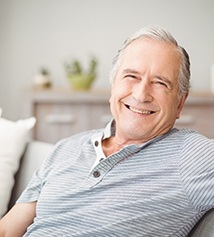 Senior man in striped shirt sitting on couch and smiling