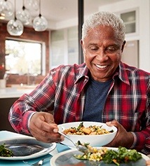Senior man filling plate at table