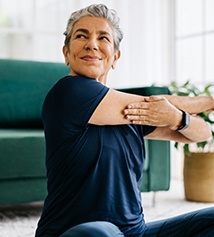 Senior woman smiling while stretching at home