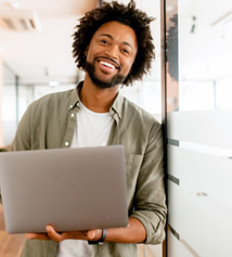 Smiling man holding laptop in office