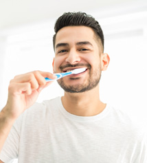 Man smiling while brushing his teeth
