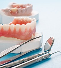 Model of denture next to dental tools