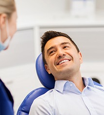 Dentist talking to smiling patient in treatment chair