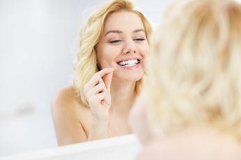 Woman flossing in the mirror 