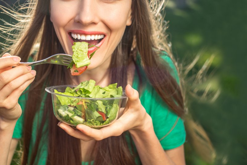 attractive young woman smiling while eating a salad