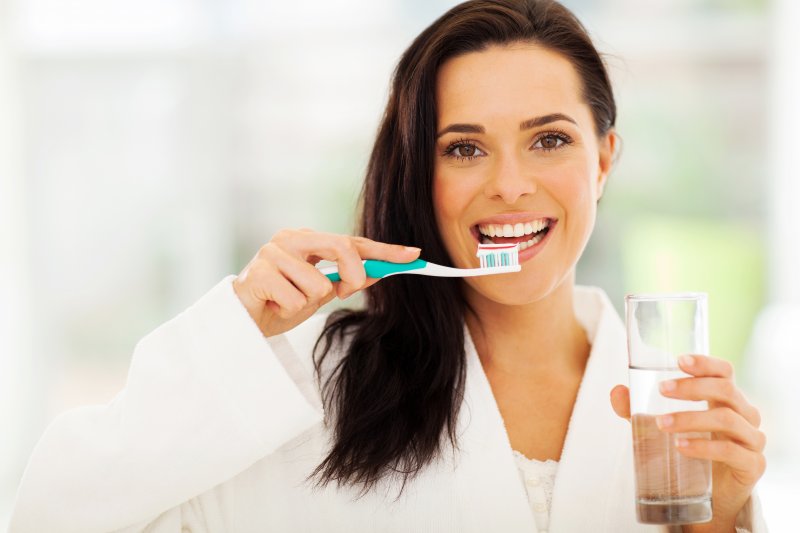 Woman smiling and brushing her teeth