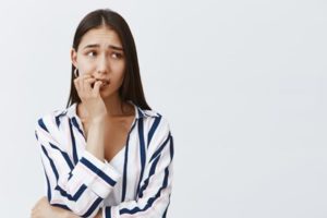 Woman wearing a striped top nervously biting her fingernails