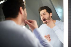 man looking at his dental crown in the mirror 