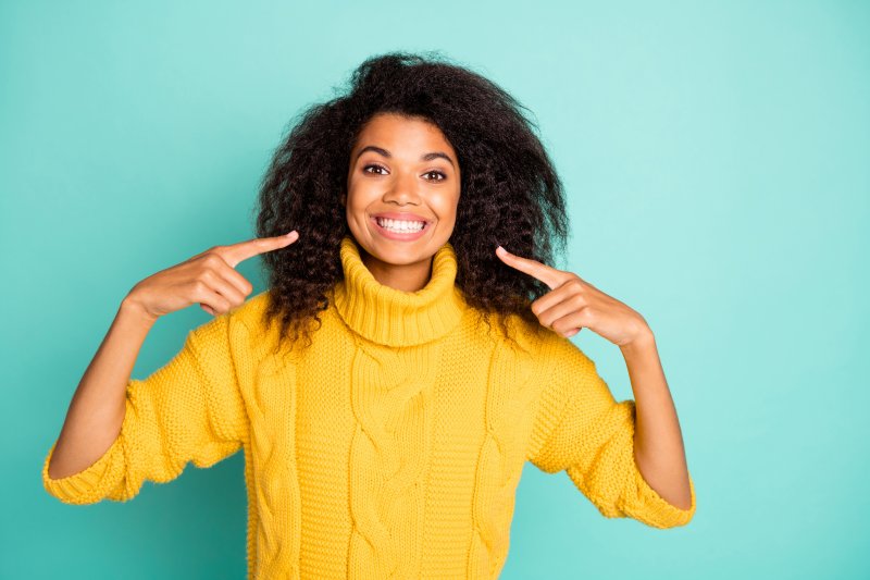 young woman smiling and pointing to teeth