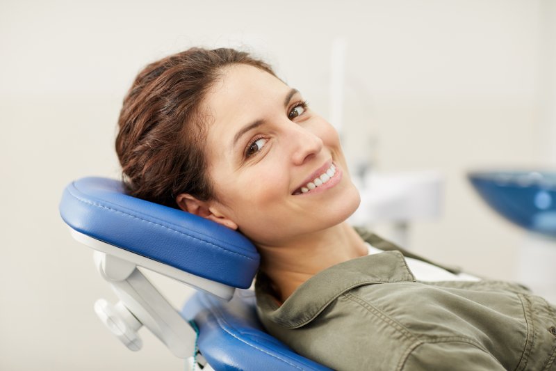 young woman smiling while sitting in dentist chair 