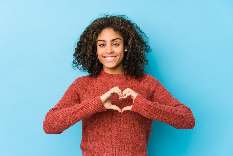 person smiling and making a heart with their hands