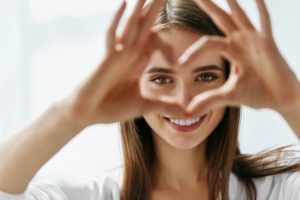 a woman smiling and shaping a heart with her hands