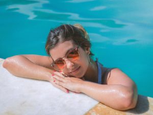 Woman in swimming pool resting her head on ledge