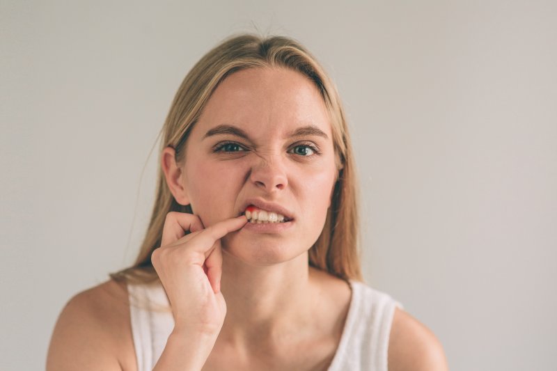 A woman testing her gum disease to see if it's tender with her pinky