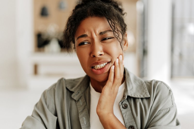 a woman holding her cheek due to tooth sensitivity