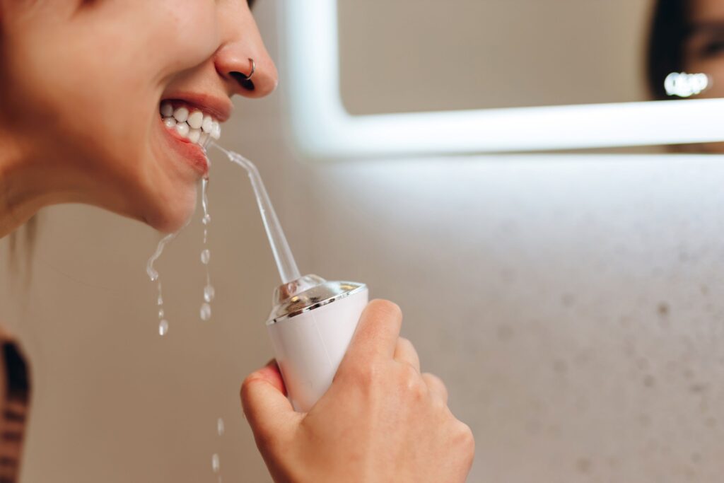 Profile view of woman cleaning teeth with water flosser