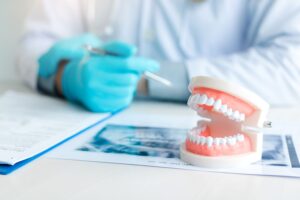 Dentist at desk with gloves on looking at papers and X-rays